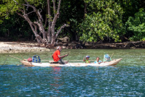 Old Papuan man and two children in an outrigger, Milne Bay PNG