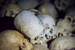 Piles of human skulls in the dark, Skull Cave, Milne Bay, PNG
