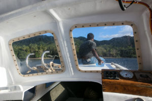 View through a boat windsceen: Papuan man and Milne Bay coastline, PNG