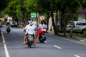 Motorcycles with pillion passengers in traditional dress, Ubud Bali