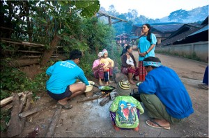 Hilltribe family squatting around a cooking fire