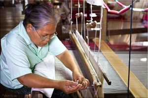 Thai woman at the head of a two-story silk loom
