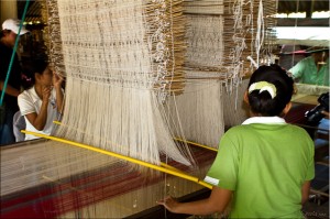 Young Thai women at the sides of a two-story silk loom