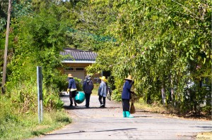 Workers in Thai straw hats and blue overalls cleaning with brooms and buckets