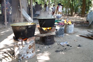 Blackened pots of boiling yellow goop on outdoor fire pots
