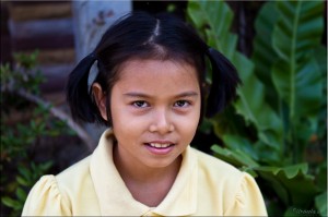 Young Thai girl with pigtails, wearing a yellow shirt