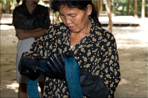 Thai woman in black rubber gloves with skein of indigo silk
