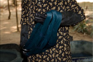 Black rubber-gloved hands with a skein of indigo silk