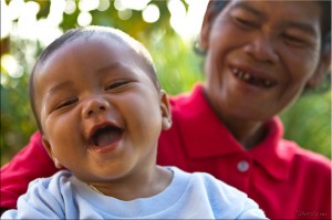 Smiling baby and elderly woman; both with few teeth