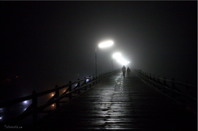 People on a wooden bridge in the dark