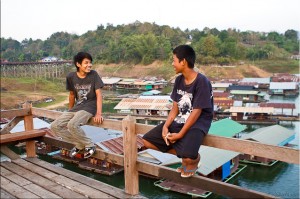 Boys sitting on the railing of the wooden bridge
