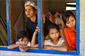 Old woman and young children at open wooden window: Laos