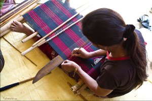Top view of a woman weaving with a back strap loom