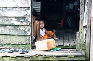 Baby inside doorway of a simple wooden house