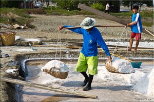Thai man carrying baskets of salt