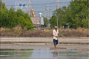 Landscape: Thai man levelling salt farm
