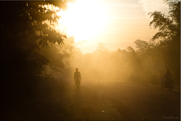 Man walking on dusty road at suntise, Attapeau, Laos