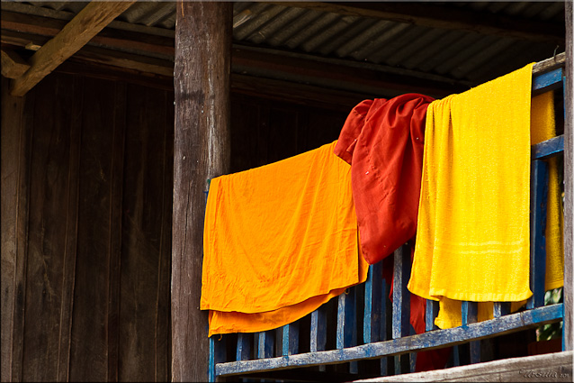 Orange and saffron cloths on a balcony rail, Attapeu, Laos