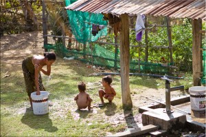 Woman in sarong bathing from a bucket