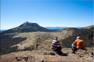 Two men sitting on Puy de Pariou looking at Puy-de-Dôme