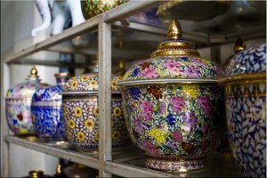 Covered Benjarong (five-coloured enamel glazed porcelain) pots on a metal shelf