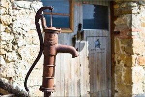 Rusty Hand-Pump in front of wooden garage doors, Camps-sur-l'Agly