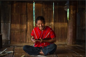Karen man in traditional tunic carving bamboo