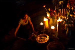 A Kmer woman lights candles and incense for temple offerings