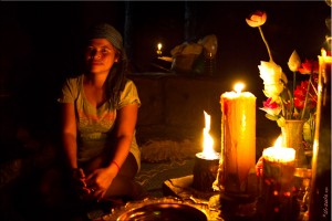 Kmeer woman seated in candle light next to a Buddhist shrine