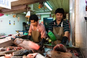 Two thai men chop and clean fish