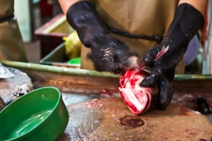 Hands in black rubber gloves scale fish