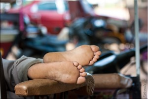 Soles of two feet on a tuk-tuk arm-rest