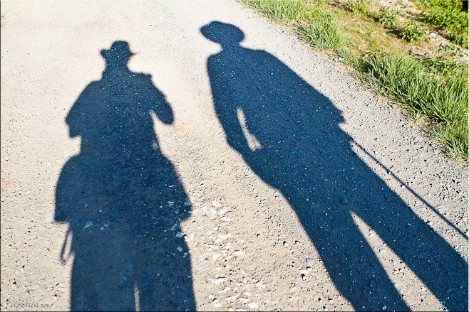 Shadows of two people on a gravel road