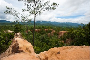 View of Pai Canyon: reddish dirt, blue hills, green growth