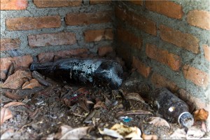 Old empty beer bottle and energy-drink bottle inside a brick memorial alcove
