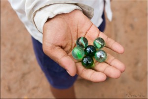 Small hand holding six cat's eye marbles.
