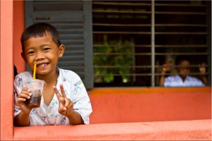 Portrait: Khmer boy with a soft-drink in a plastic cup on a school verandah