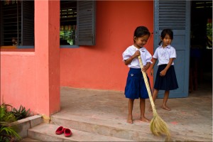 Young khmer girls in school uniform sweep a school verandah.