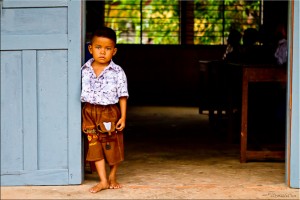 Young khmer boy stands in a classroom doorway.