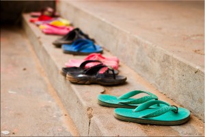 Colourful plastic flip-flops lined up on a school step.