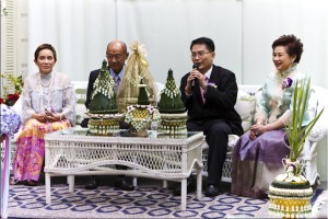 Two Thai couples, dressed in formal attire, seated on a sofa