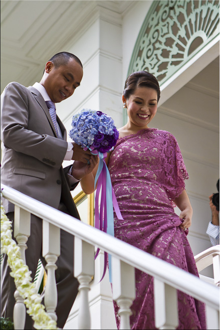 Young Thai man and woman in formal dress descending a staircase.