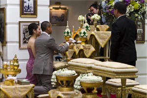 Kneeling thai couple lighting candles on a tiered platform.