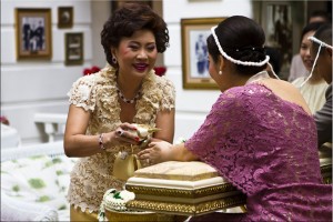 Using a conch shell, a thai woman pours holy water over the hands of a newlywed bride.