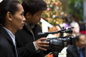 Portrait: Two young Thai men in profile, with a large camera.