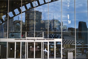 Australian Maritime Museum glass front with reflections of central Sydney buildings.
