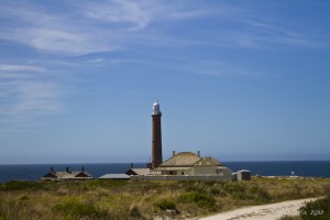 Homestead and lighthouse, circa 1800s, against a blue Australian sky.