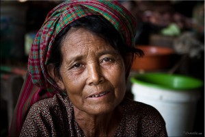 Portrait: Elderly Khmer woman in a woven checkered cotton headscarf.