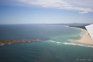 Turquoise waters between an island and a sand bar.