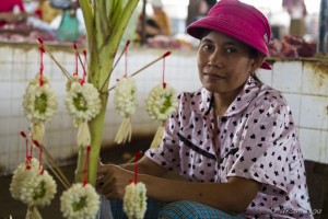 Portrait: Khmer woman in a red hat behind jasmine garlands